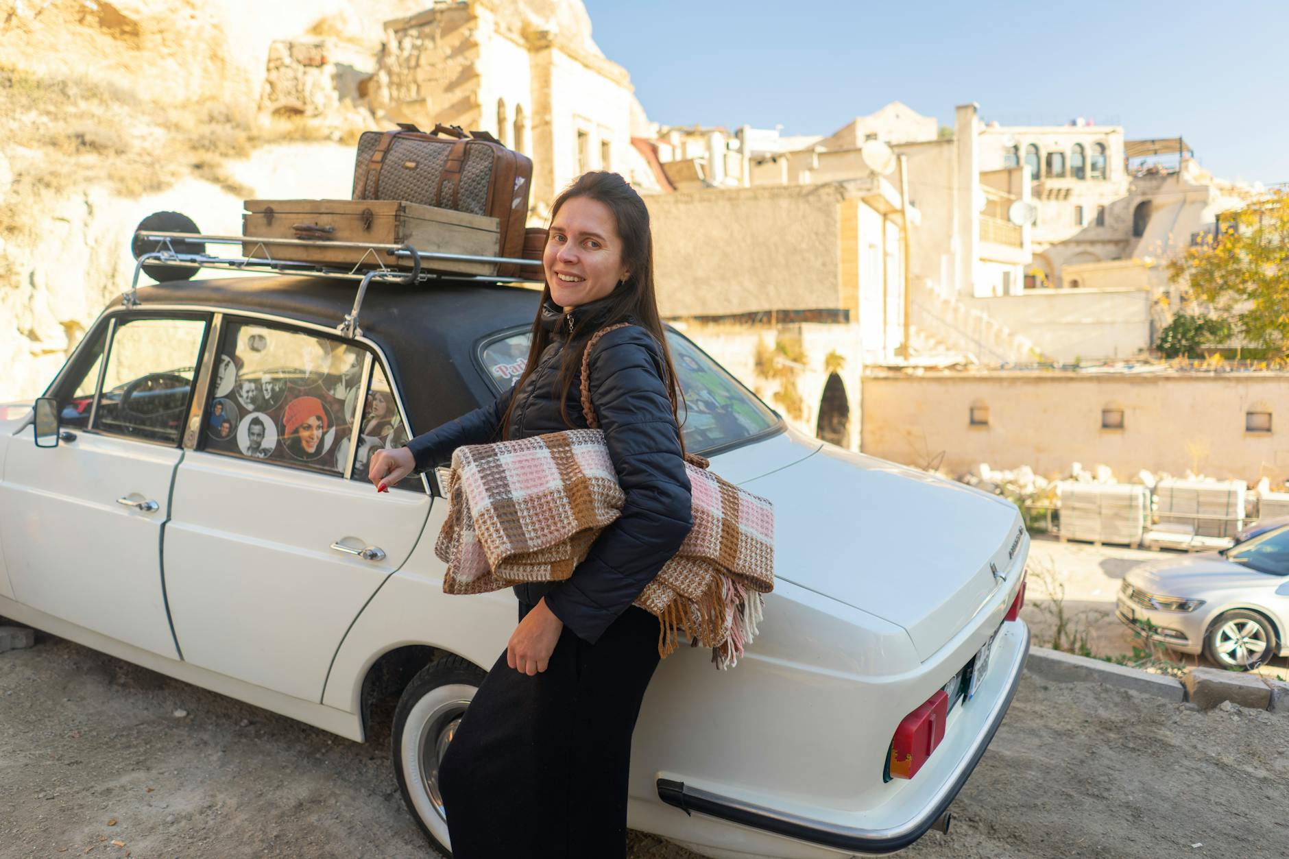 Kobieta przy zabytkowym aucie z bagażem na słonecznej drodze w Kapadocji