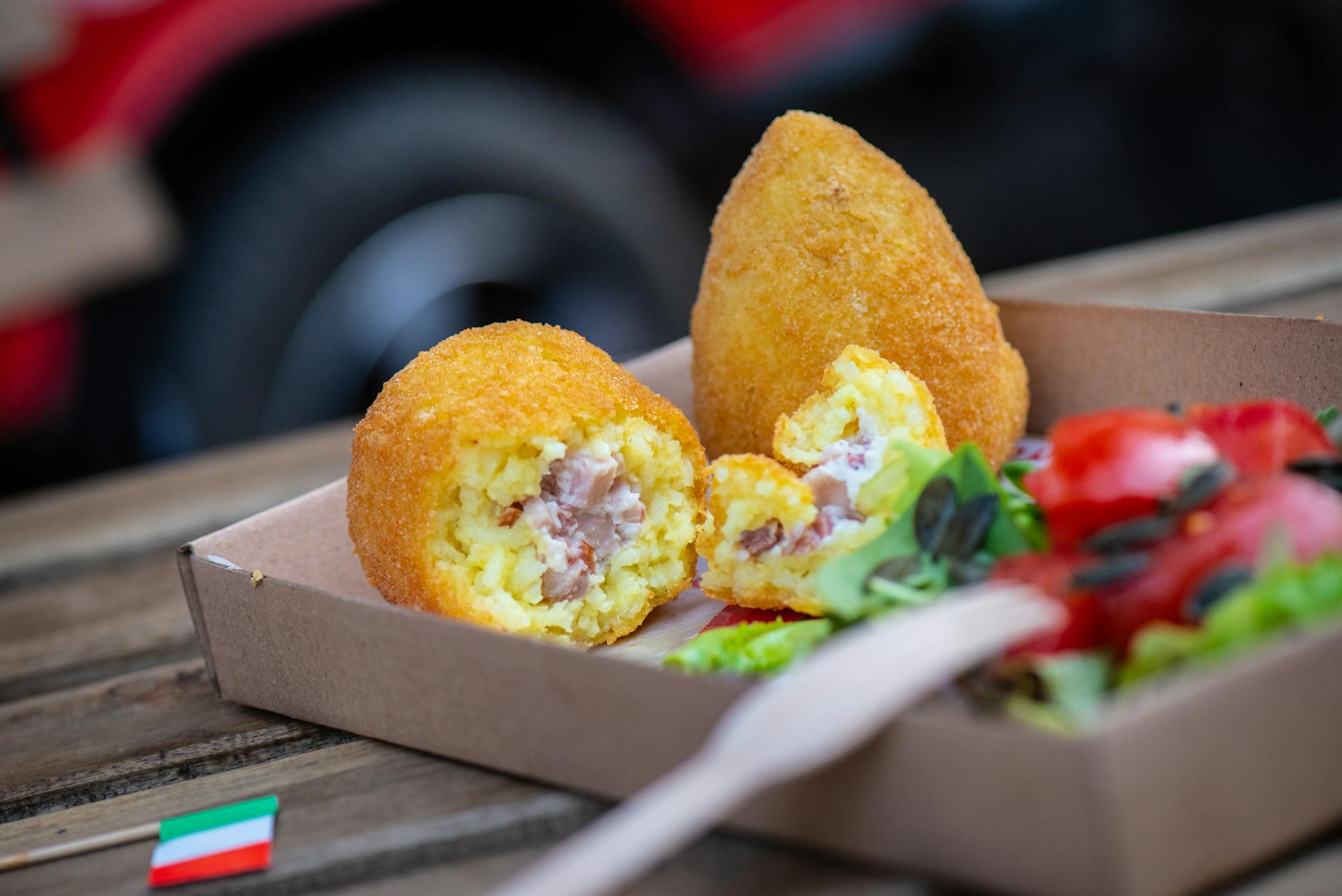 Zbliżenie na złociste arancini z sałatką w naturalnym świetle Zbliżenie na złociste arancini z sałatką w naturalnym świetle