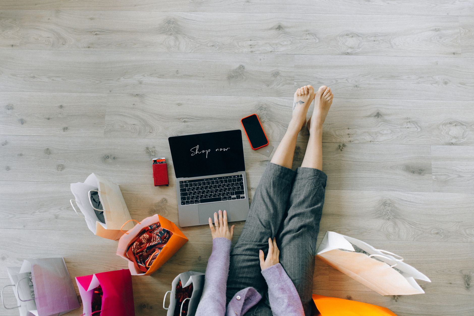 Kobieta robi zakupy online na laptopie obok toreb papierowych