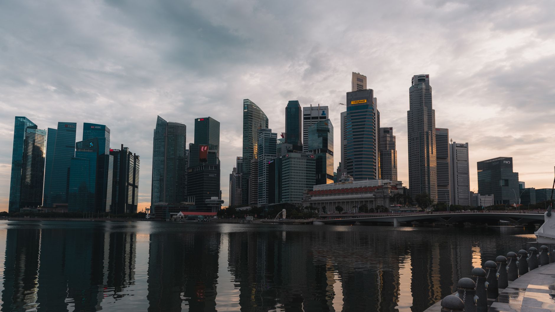 Panorama wieżowców Singapuru odbijających się w wodzie o zmierzchu