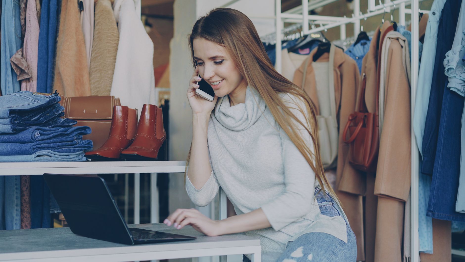 Uśmiechnięta kobieta w butiku kupuje ubrania online na laptopie